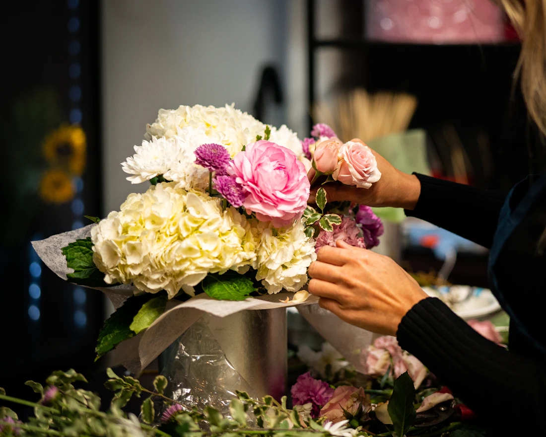 Hands arranging fresh flowers in a vase